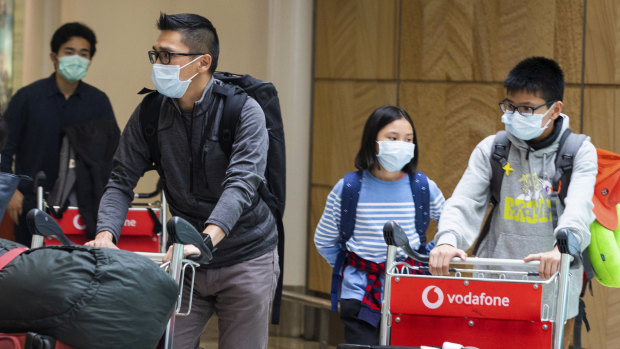 Passengers arrive at Sydney Airport on Monday wearing masks to avoid contact with the virus. 