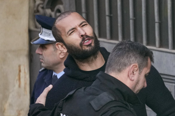 Police officers escort Andrew Tate to the Court of Appeal in Bucharest, Romania on February 1.