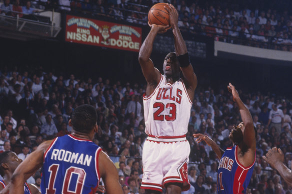 Michael Jordan jumps to shoot a basket against the Pistons, with long-time foe Isiah Thomas next to him.