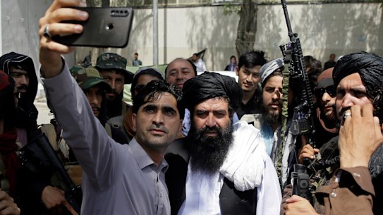 An Afghan takes a selfie with Taliban fighters on patrol in Kabul on Thursday.