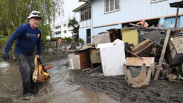 Chris Mitchell removes flood damaged items out of his father in-law's house in the Townsville suburb of Rosslea.