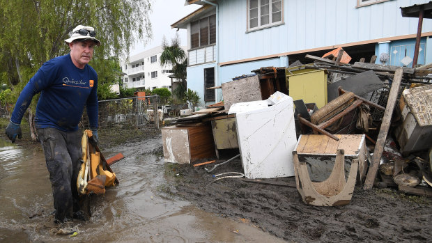 Chris Mitchell removes flood damaged items out of his father in-law's house in the Townsville suburb of Rosslea.