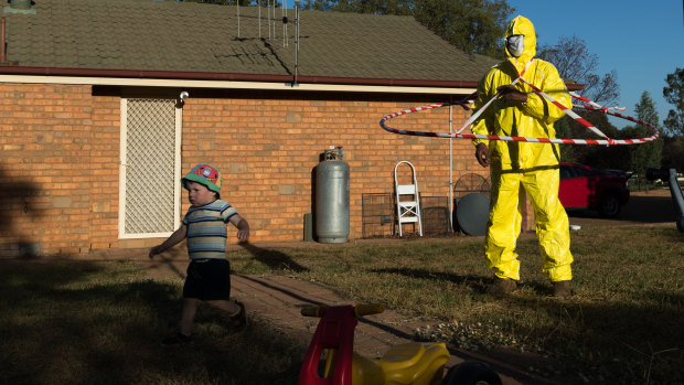 Harvey Kleinig, 2, runs away scared from his grandfather, Jeff Kleinig, who is wearing his tongue-in-cheek protective suit he designed in response to the coronavirus pandemic, in Dubbo.