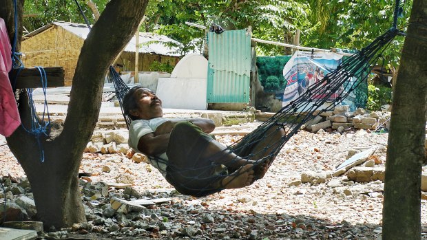 A villager from Nipah in North Lombok rests in a hammock in front of the ruins of what used to be his big family house.
