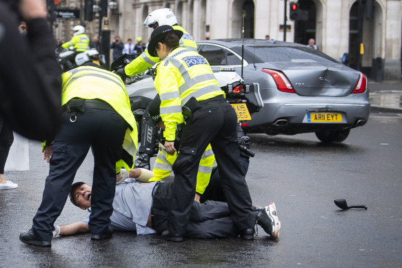 Police detain a man after running in front of Britain's Prime Minister Boris Johnson's car, right.