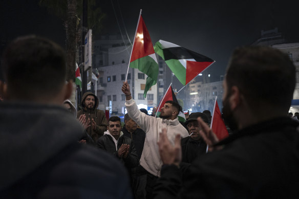 People wave Palestinian flags while celebrating the announcement of a ceasefire in Ramallah in the West Bank.