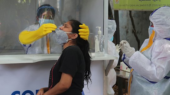 A health worker takes a nasal swab sample to test for COVID-19 in Hyderabad, India on Friday.