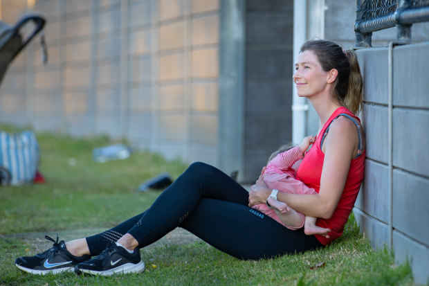 Grace Preuss takes a minute to breastfeed her daughter at footy training.