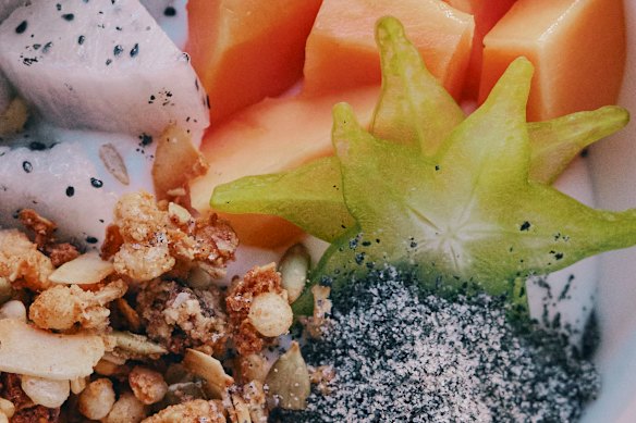Yoghurt bowl with black sesame praline and tropical fruit.