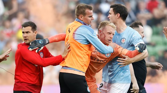 Tom Glover is escorted from the pitch by teammates after fans stormed the pitch. 