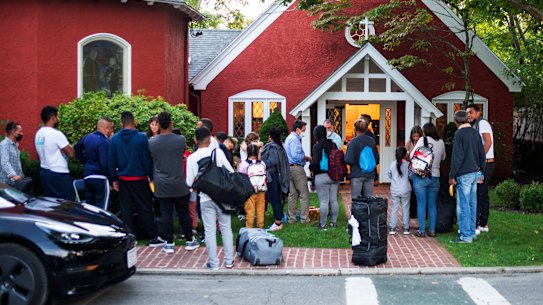 Immigrants gather with their belongings outside a church on Martha’s Vineyard.