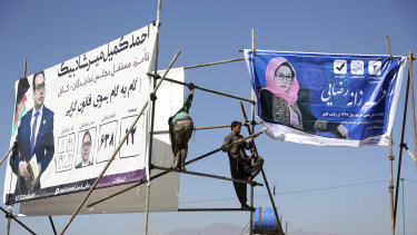 Afghan men install election posters of parliamentarian candidates during the elections campaign for the election in Kabul, Afghanistan.