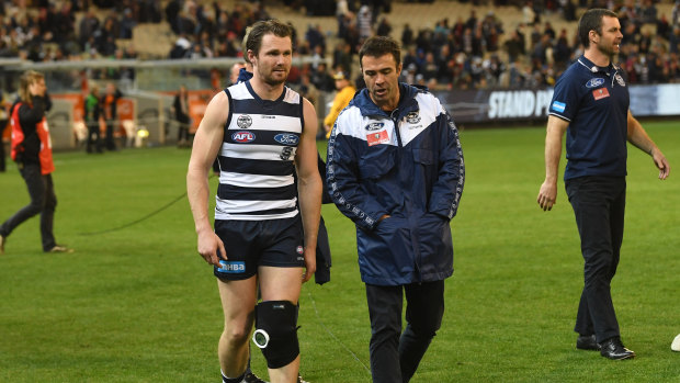 Patrick Dangerfield talks with coach Chris Scott after injurying his knee against the Bombers.