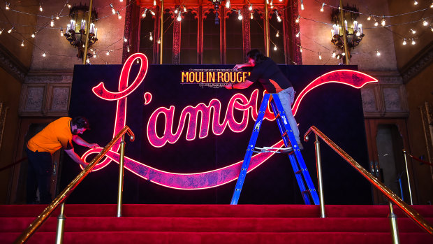 Nelson Pollard (left) and Matt Spargo install a recreation of Baz Luhrmann’s glowing red L’amour sign at the Regent to celebrate the return of theatre to Melbourne. 