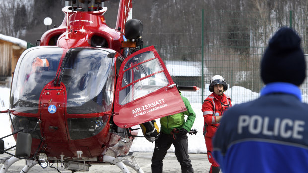 A police officer looking at an Air Zermatt helicopter landing after searching for survivors of an earlier avalanche in early April.
