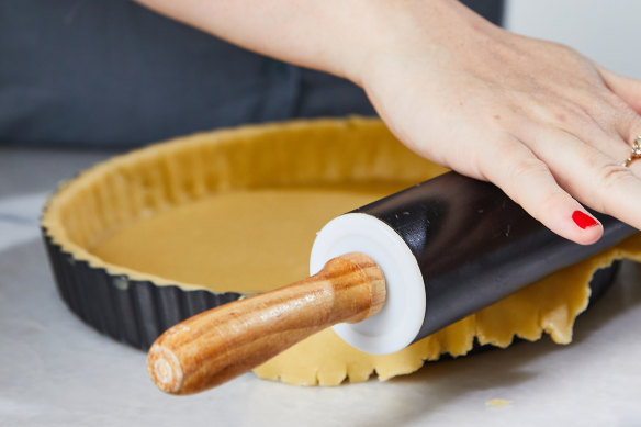 Trim excess pastry from the tart shell by running a rolling pin over the tin.
