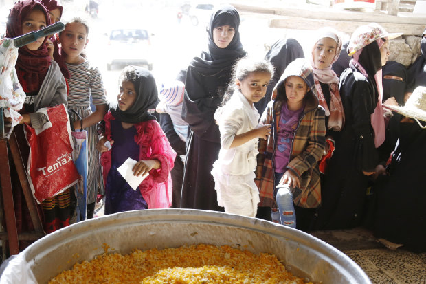 People wait for food aid in Yemen during a truce in fighting in April.