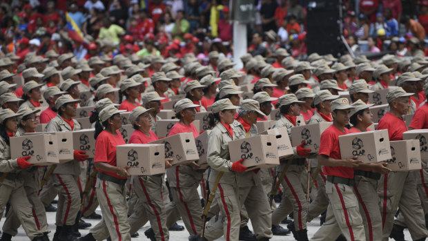 Members of the National Bolivarian Militia march with government issue food distribution boxes, known by the Spanish acronym CLAP, during a Venezuela Independence Day military parade in Caracas.