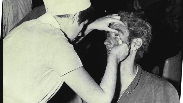 A nurse brushes ashes from the eyes of a weary firefighter at Springwood, November 29, 1968