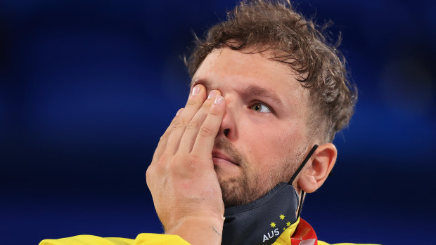 Dylan Alcott wipes away a tear on the podium in Tokyo.