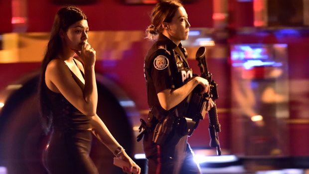 A woman is escorted by police away from the Toronto shooting scene.