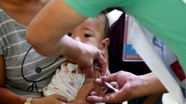 Philippine National Red Cross and Health Department volunteers conduct house-to-house measles vaccinations at an informal settlers' community in Manila, Philippines.