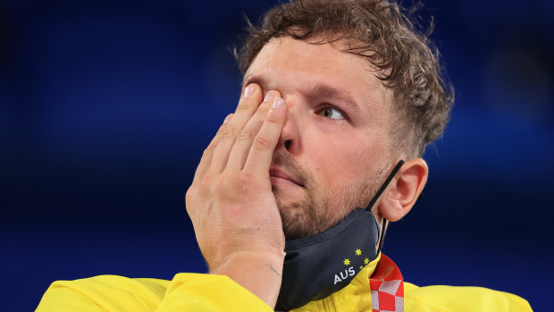 Dylan Alcott wipes away a tear on the podium in Tokyo.