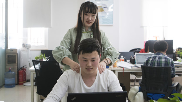 Shen Yue massages the shoulders of one of her colleagues at Chainfin.com in Beijing.
