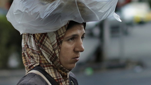 A woman carries bread in Damascus in 2019. Research shows exchange rate distortions allow the government of Bashar Assad to divert at least $US100 million of international aid to its coffers.