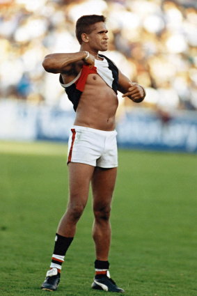 St Kilda player Nicky Winmar points to his skin in response to a racist taunt from the crowd in 1993. This enduring image is part of the You’re The Voice campaign video.
