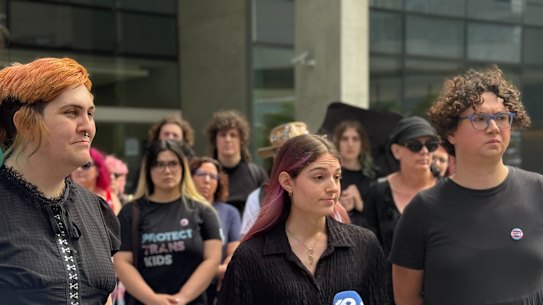 Protesters rally outside Brisbane Supreme Court to support the parent of a trans child taking Queensland Health to court over its gender-affirming treatment ban.