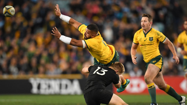 Bruising: Jack Goodhue goes low and hard into the legs of Tolu Latu during the Bledisloe Cup opener in Sydney. 