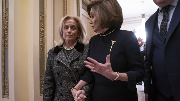 Speaker of the House Nancy Pelosi holds hands with Representative Debbie Dingell, whose deceased husband Trump suggested was in hell. 