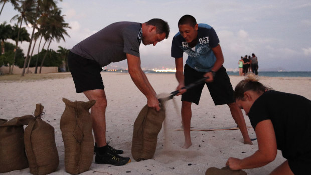 People fill up sand bags that will be used to help protect their home in preparation for Hurricane Lane.