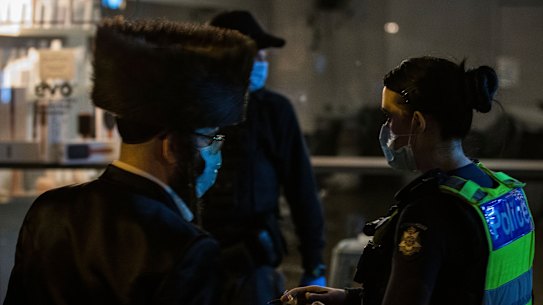 Members of Victoria Police take down the details of people outside the illegal gathering.