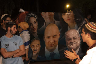 Israeli right-wing activists chant slogans and hold signs showing Naftali Bennett, centre, with Arab politicians Ahmad Tibi, right, and Mansour Abbas, left, during a demonstration against a possible new government in Tel Aviv.