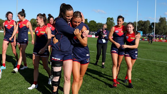 Daisy Pearce, wearing a leg brace, hugs teammate Eliza McNamara after the Demons defeated the Lions.
