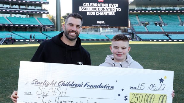 Roosters captain James Tedesco holds a cheque donation with Starlight child Jack (14) for Swysh at the SCG.