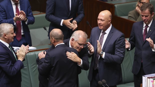 Treasurer Josh Frydenberg is congratulated by Prime Minister Scott Morrison and other colleagues after delivering his budget speech.