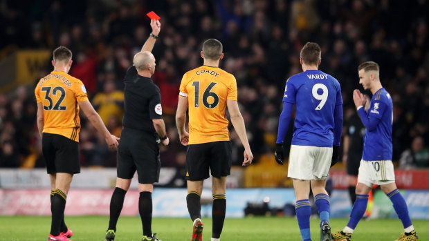 Referee Mike Dean shows Hamza Choudhury of Leicester City (obscured) a red card.