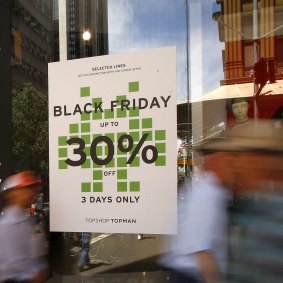  Pedestrians walk past in front of a Black Friday sale advertisement in Sydney, Australia. 