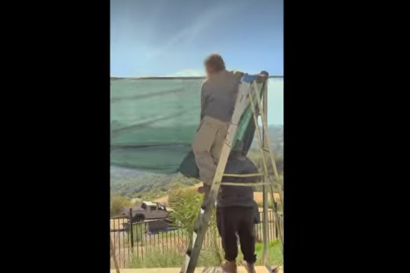 A screenshot of people putting up material to block the views of paparazzi trying to take photos of the couple at Tyler Perry’s house in LA where they were living.