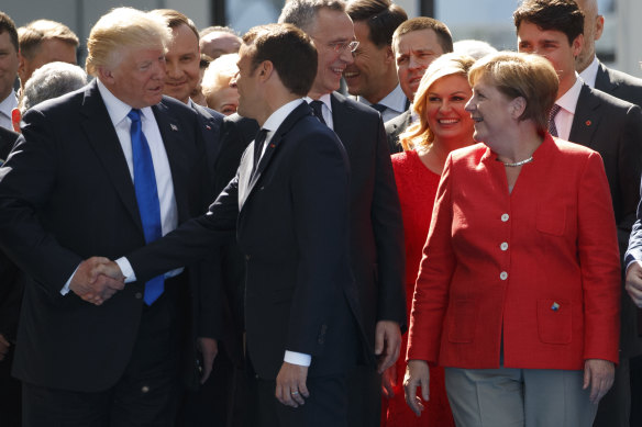 Germany’s then-chancellor Angela Merkel watches as Trump shakes hands with Macron in 2017.
