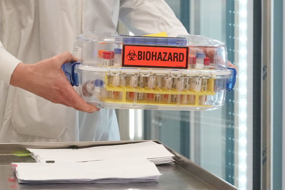 A worker moves a tray of samples being tested for COVID-19 into a cooler at the Washington State’s Public Health Laboratory for genome sequencing.