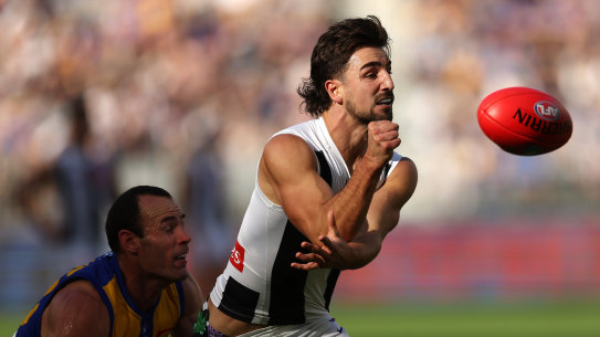 Josh Daicos of the Magpies handpasses the ball under pressure from Shannon Hurn of the Eagles.