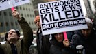 People hold signs at a vigil outside the Australian consulate in New York City after the Bondi massacre.