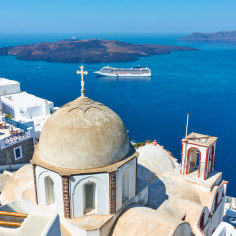 Fira town in Santorini island in Greece with cruise ship in the background.