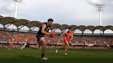 Still got the Blues: Carlton's Dale Thomas races up the wing at Metricon Stadium on the Gold Coast as Suns' Ben Ainsworth closes in.