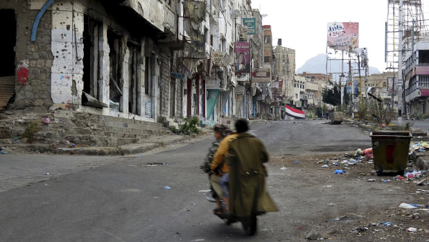 Men ride through streets wrecked by fighting in Taiz, Yemen in this February.