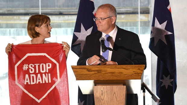 An Adani protester takes to the stage during a Brisbane speech by Prime Minister Scott Morrison this month.